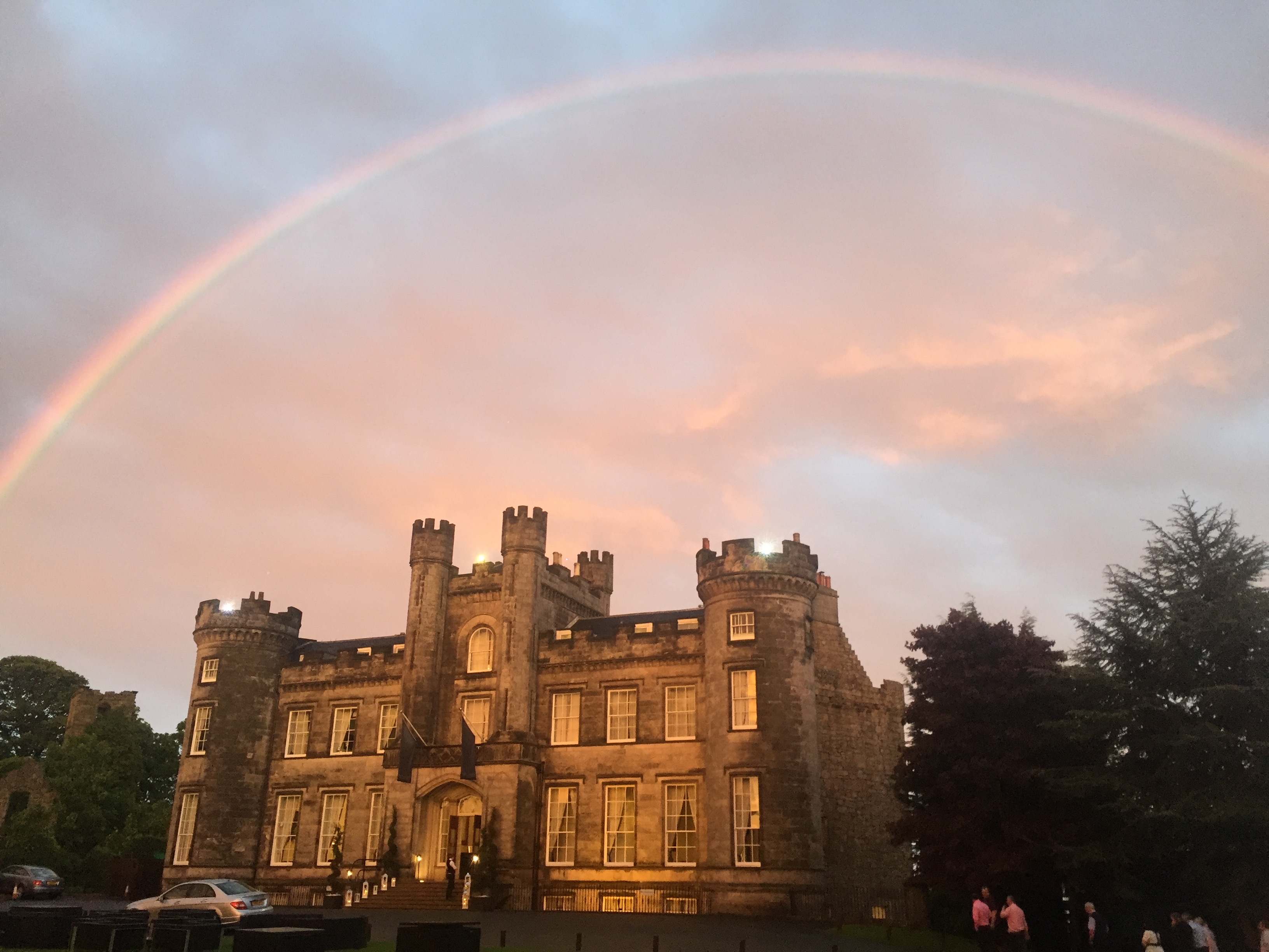 Castle beneath a rainbow at sunset.