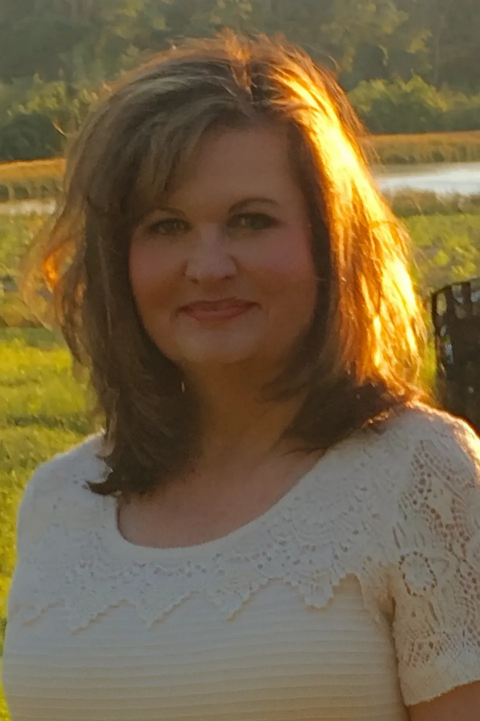 Woman smiling outdoors during golden hour.