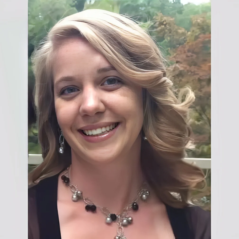 Smiling woman with curled blonde hair and a necklace.